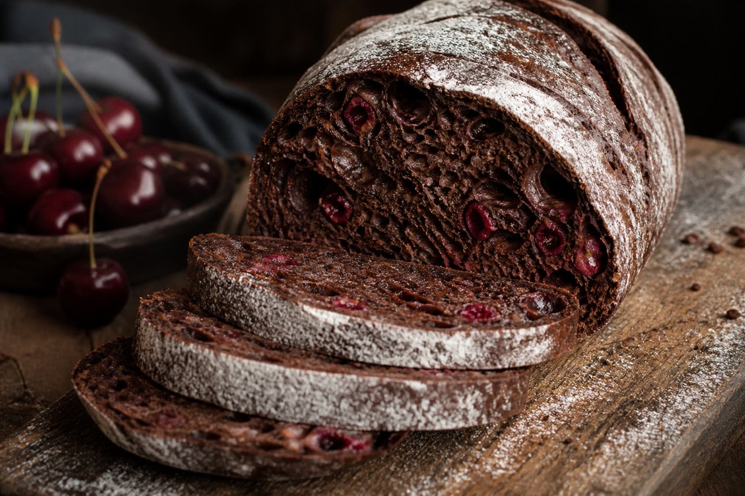 Dark cocoa gluten-free sourdough boule sliced to show dried cherries in the crumb