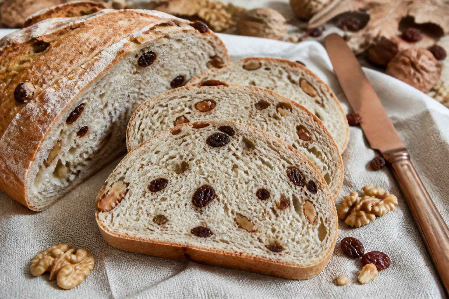 Gluten-free walnut raisin sourdough loaf sliced to show nuts and raisins in the crumb